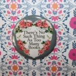 Photo of a button reading, "There's no such thing as too many books"
