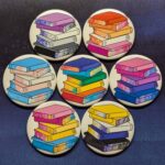 Photo of several buttons showing stacks of books in pride flag colors