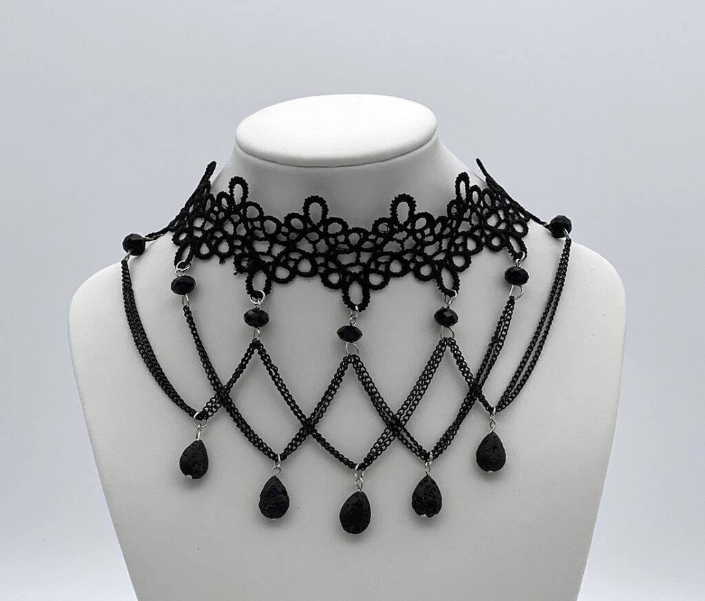 Photo of a black, lacy, choker-style necklace with several black pendants hanging from thin black chains.