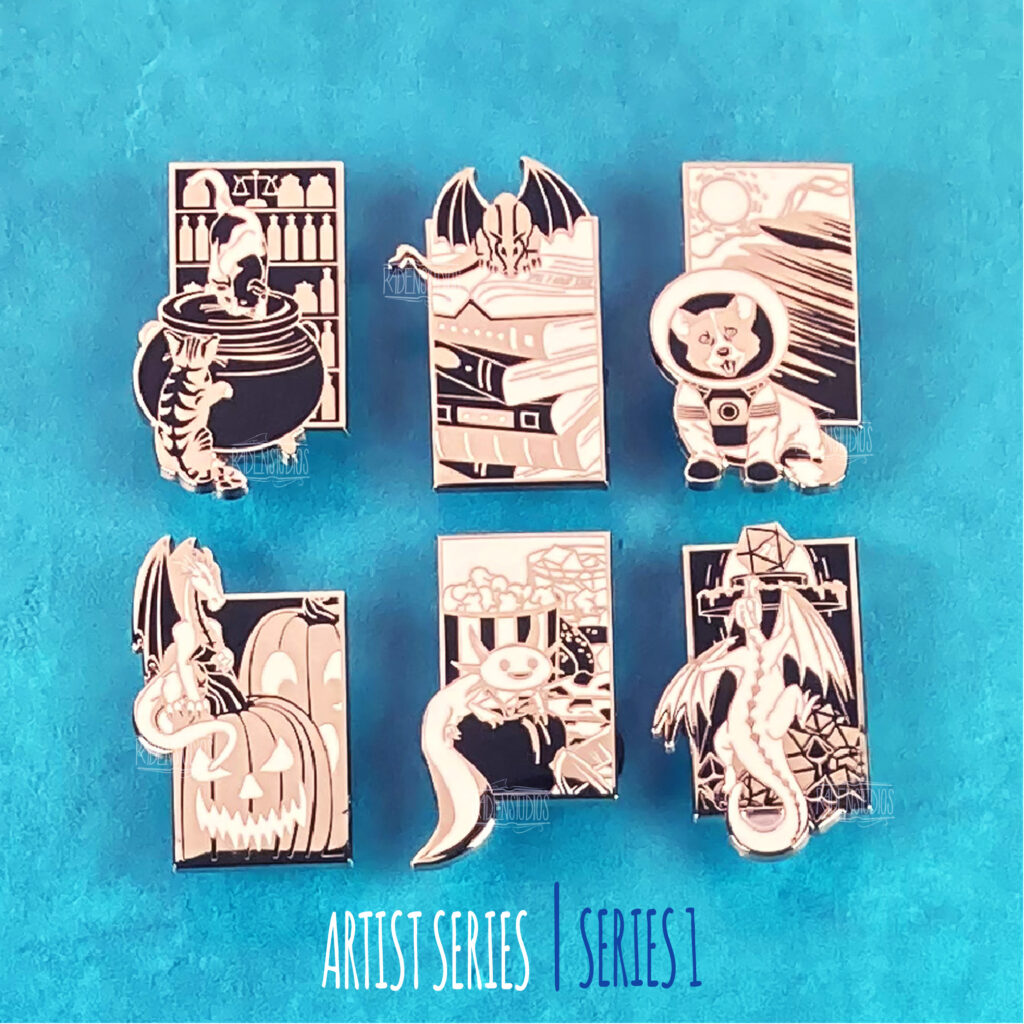 A set of six enamel pins featuring designs of cats, dragons, a dog in a spacesuit, and an axolotl