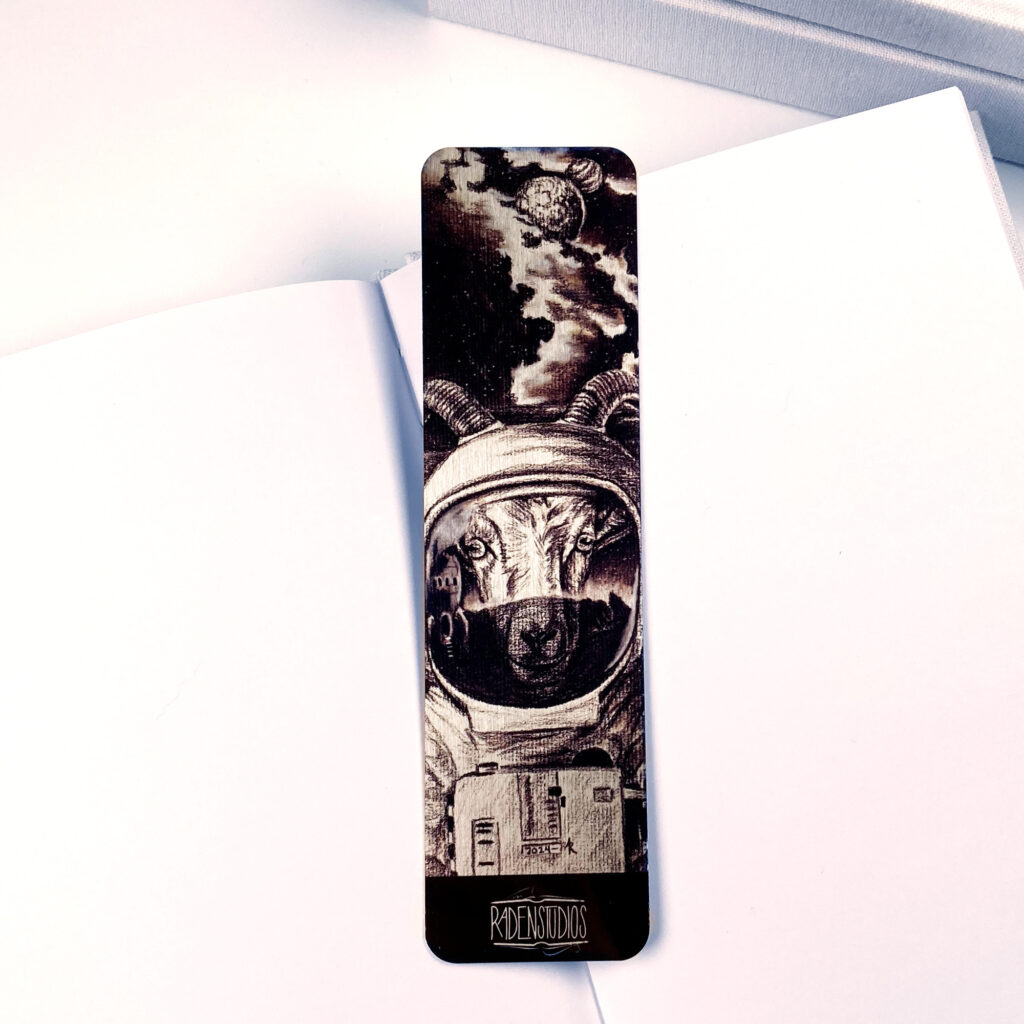 A bookmark featuring a charcoal drawing of a goat in a spacesuit.