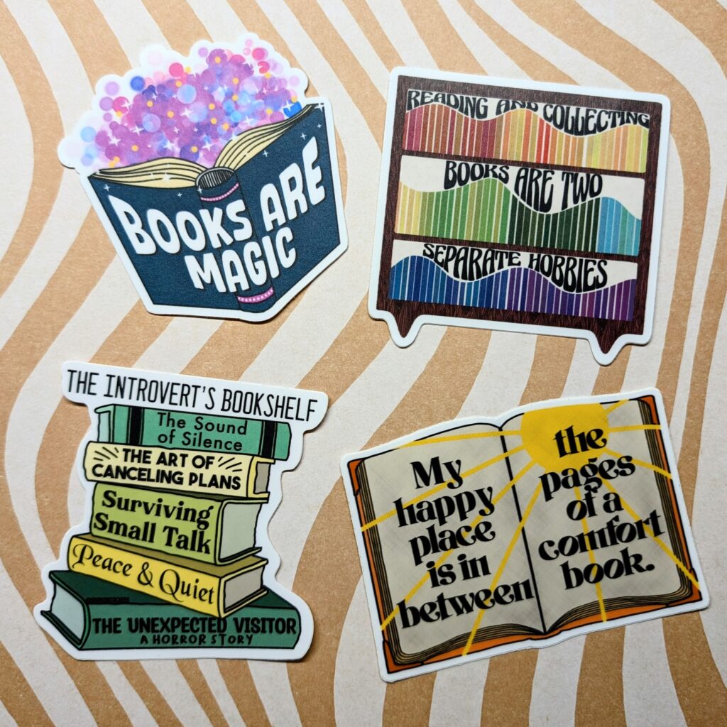 Four book-themed stickers. "Books Are Magic," Reading and Collecting Books Are Two Separate Hobbies," "The Introvert's Bookshelf," "My happy place is between the pages of a comfort book."